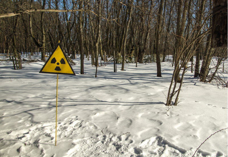 in einem verschneiten Wald steht ein Warnschild vor Radioaktivität