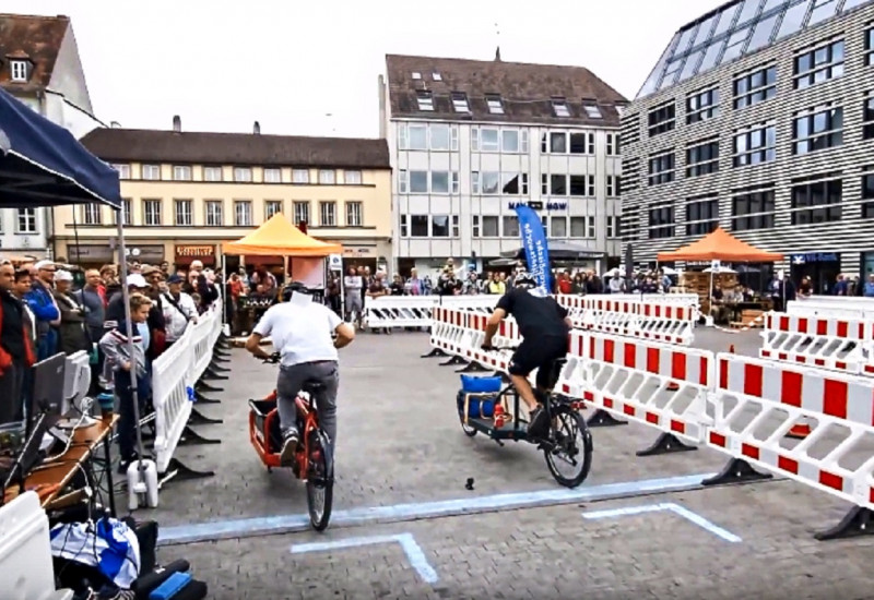 Zwei Lastenradfahrende treten auf dem Marktplatz in Würzburg gegeneinander an. Absperrung ist zu sehen. 