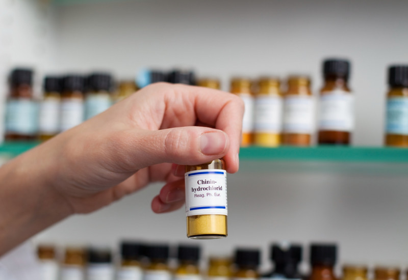 ein Apotheken-Mitarbeiter nimmt ein beschriftetes Fläschchen aus dem Regal