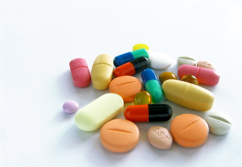 Tabletten in verschiedenen Formen und Farben liegen auf einem weißen Untergrund