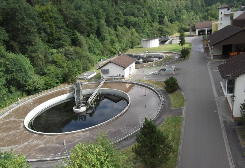 zwei Runde Wasserbecken einer Kläranlage am Waldrand