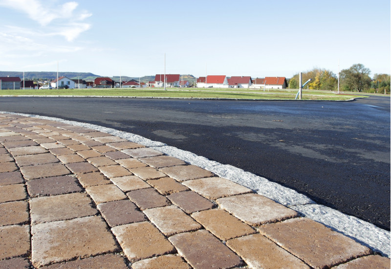asphaltic street and paved footway, in the background new houses