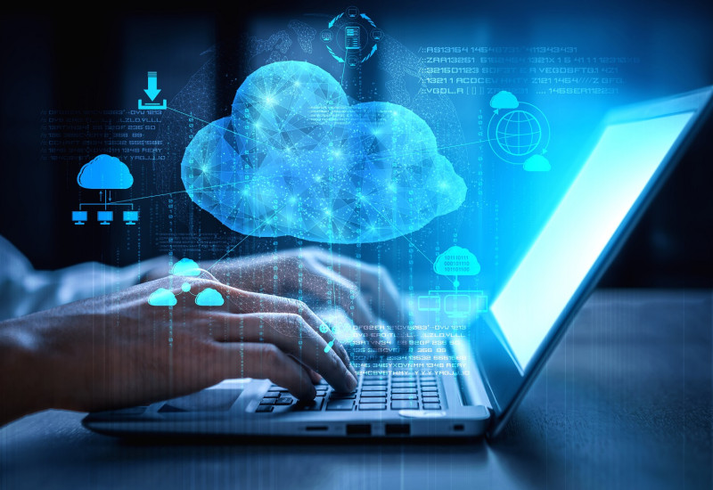 jemand tippt auf einem Laptop, darüber Symbole für Cloud Computing wie Wolken und Download-Pfeil