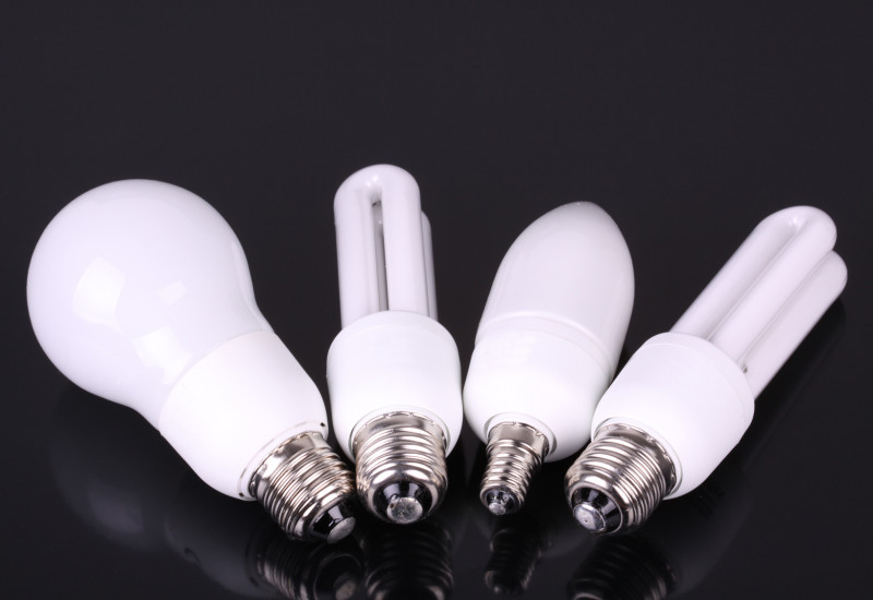 Zwei LED- und zwei Kompaktleuchtstofflampen auf einer schwarzen Oberfläche