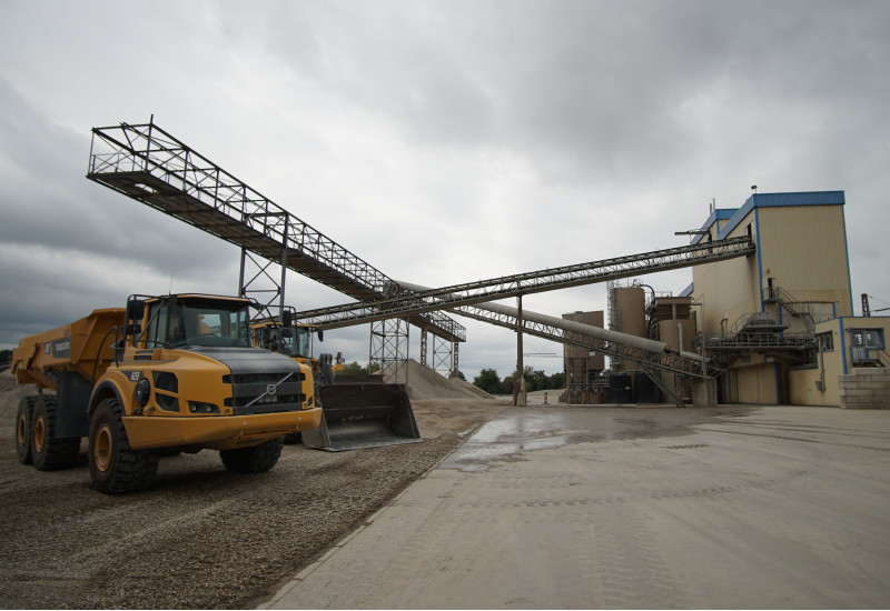 Foto einer Industrieanlage, davor zerkleinertes Gestein und ein Muldenkipper