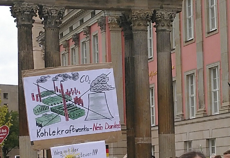 vor dem Brandenburger Landtag demonstrieren Menschen mit Protestplakaten gegen Kohlekraftwerke und die Besteuerung von Strom aus Photovoltaik