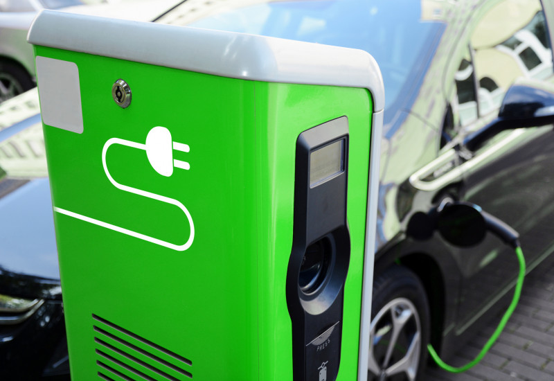 ein Elektroauto tankt Strom an einer grünen Ladesäule