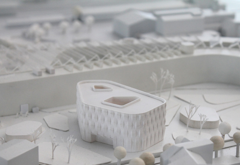 von Architekten gebautes, ganz in weiß gehaltenes Modell eines modernen vierstöckigen, polygonalen Flachbaus und seiner Umgebung