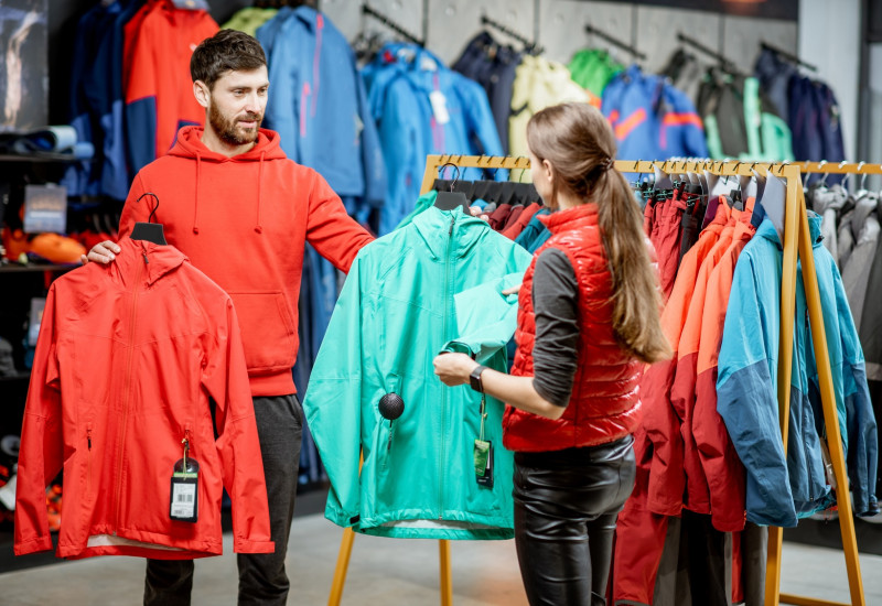 ein junges Pärchen sucht in einem Geschäft zusammen eine wetterfeste Jacke aus