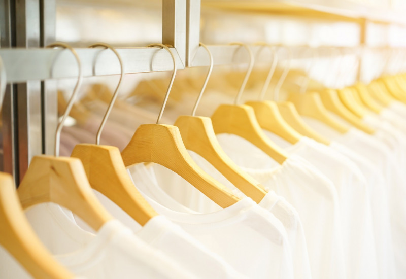 in einem Geschäft hängen viele weiße T-Shirts auf Bügeln an einer Stange