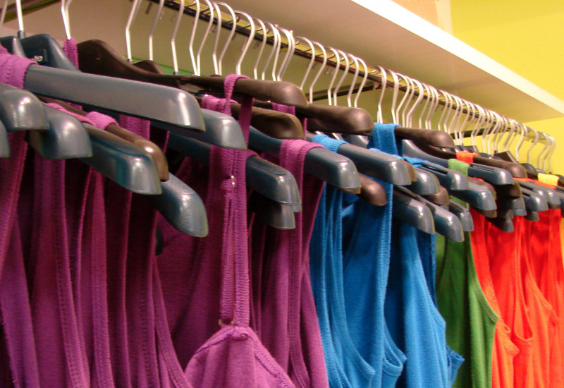pink, blue, green, red and yellow tops hanging on clothes hangers in a shop