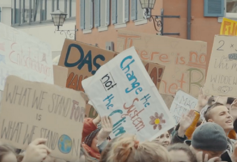 Jugendliche auf einer Demonstration halten Plakate für mehr Klimaschutz in die Luft 