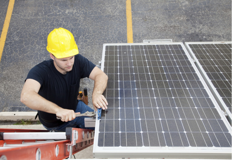 Arbeiter mit gelbem Schutzhelm arbeitet an einer Solaranlage