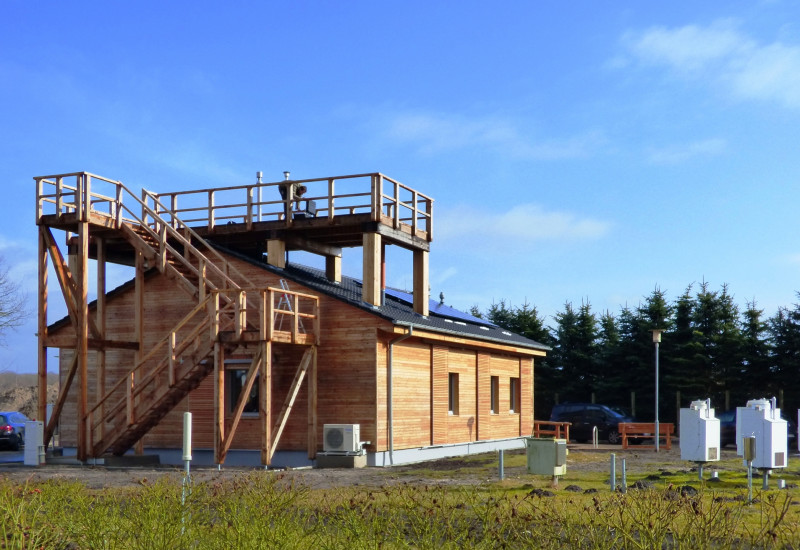 einstöckiges Holzhaus, eine Treppenanlage führt zu einer Plattform auf dem Dach