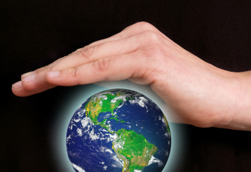 Person holding protective hands over and under a floating, bright globe