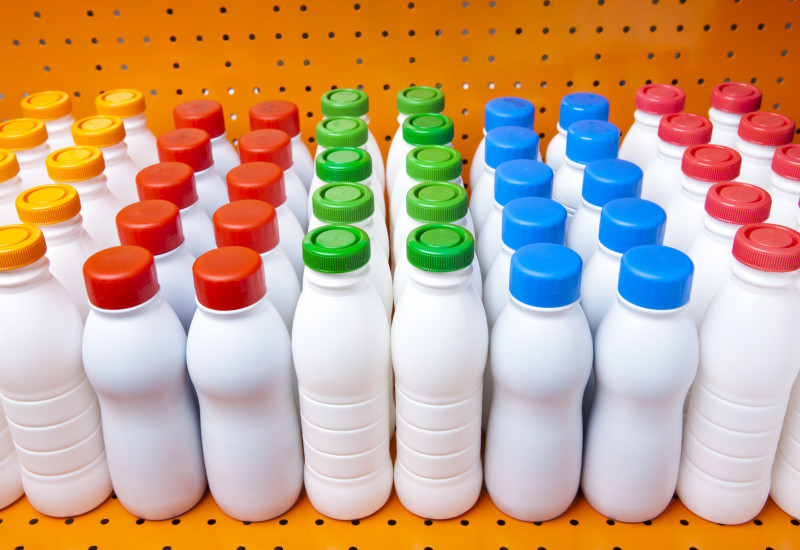 weiße, noch unbedruckte Plastikflaschen wie für Trinkjoghurt in einem Regal