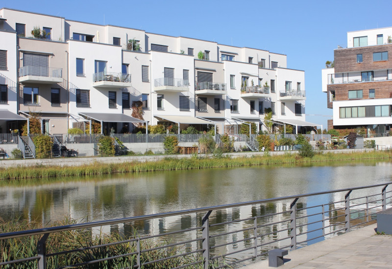along a canal in the city are white, four-storey houses in the Bauhaus style with roof terraces, balconies and small gardens with sunshades