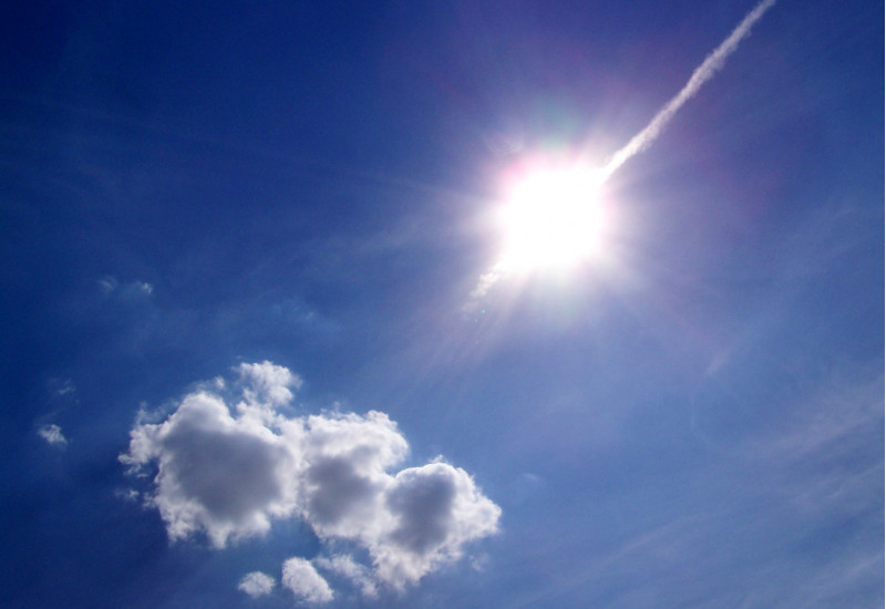 strahlende Sonne an einem blauen Himmel mit Schönwetterwolke
