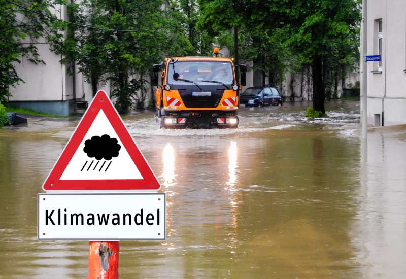 in einer überfluteten Straße in der Stadt steht ein Warnschild vor Starkregen durch Klimawandel