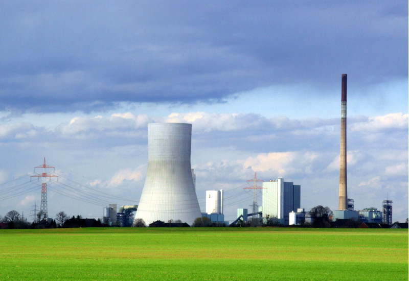 Kraftwerk mit einem Schlot und einem Kühlturm, daneben ist eine Energiefreileitung zu sehen