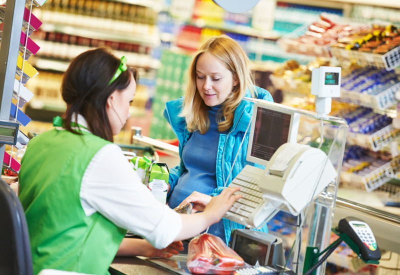 eine Frau bezahlt in einem Supermarkt ihren Einkauf bei der Kassiererin