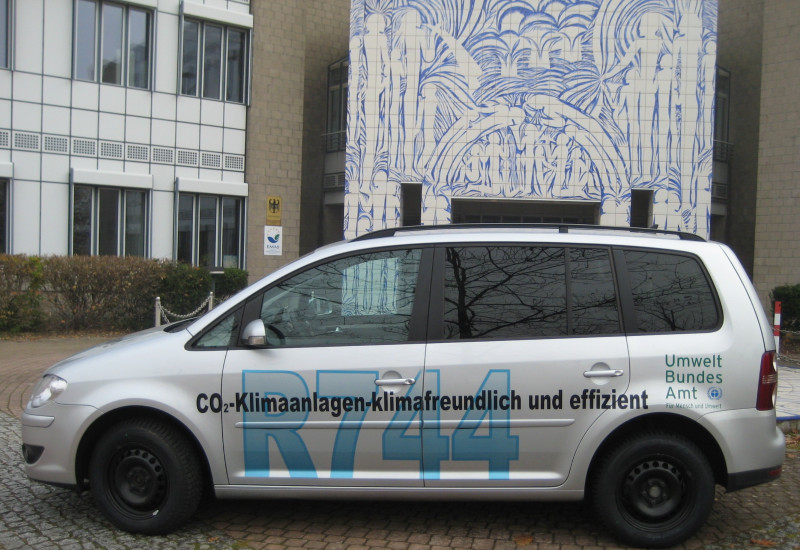 silbergraues Auto mit der Aufschrift "CO₂-Klimaanlagen - klimafreundlich und effizient, R744" und dem Logo des Umweltbundesamtes