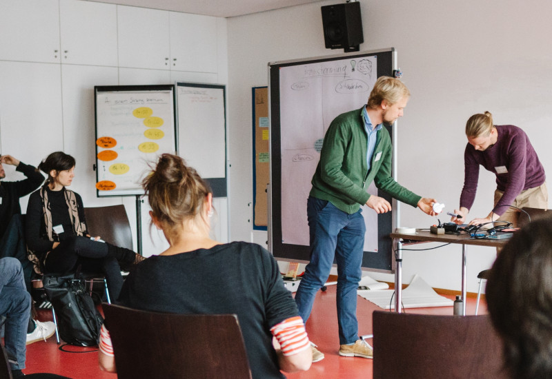 fünf Personen in einem Raum mit Flipcharts