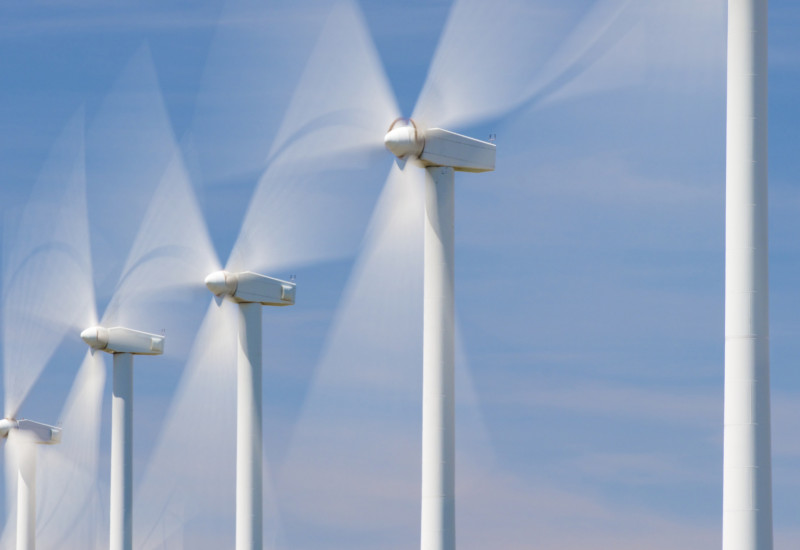 Windkraftanlagen drehen sich vor blauem Himmel