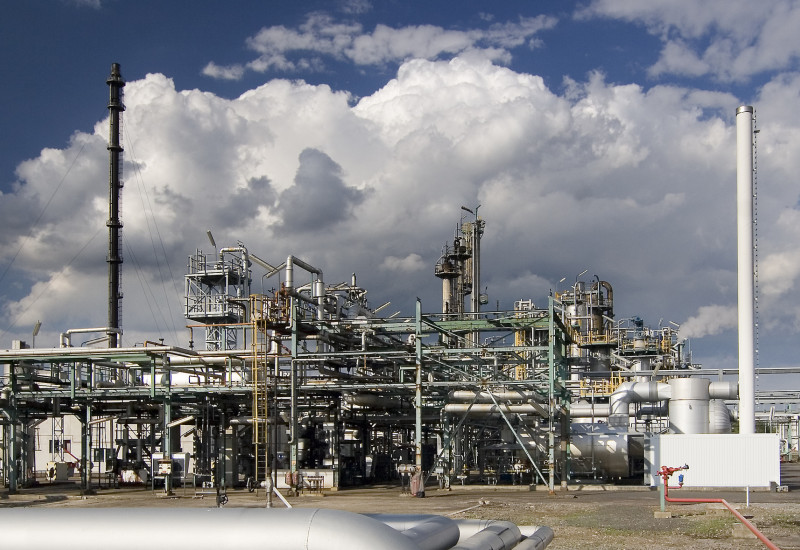 Nahaufnahme einer Chemieanlage vor wolkigem Himmel