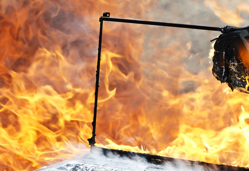 Ein brennender Laptop, im Hintergrund Feuer