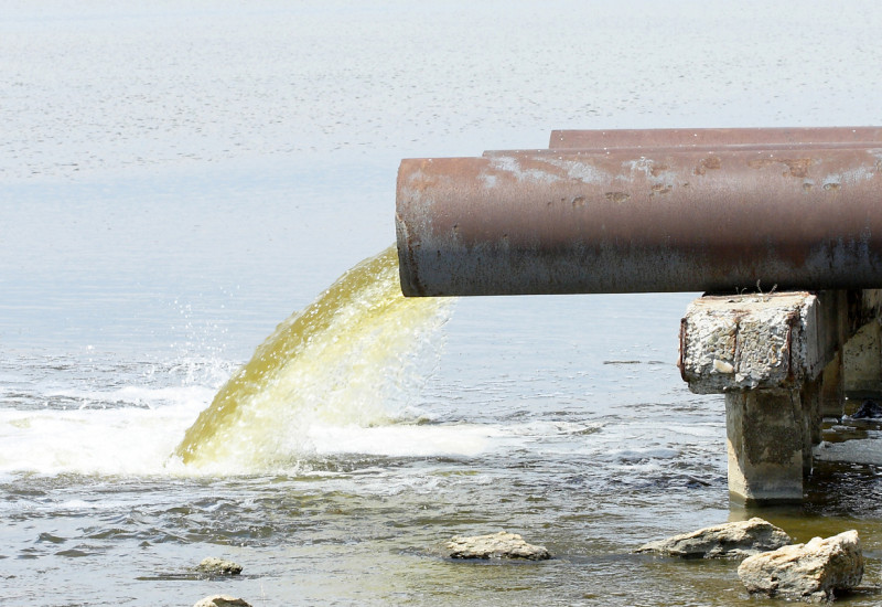 Aus einem Rohr fließt Abwasser in ein Gewässer