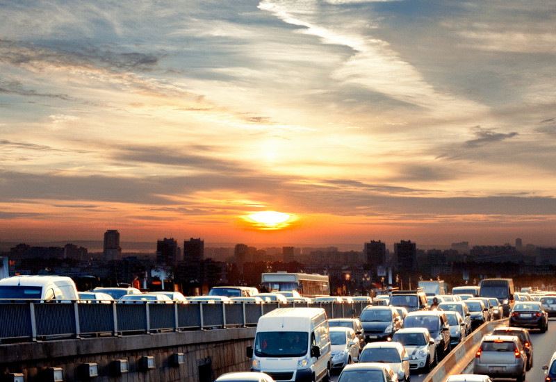 Stau auf der Autobahn am Abend. Ein Sonnenuntergang ist am Horizont zu sehen. 