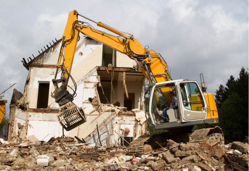 Bagger steht vor einem Abbruchhaus