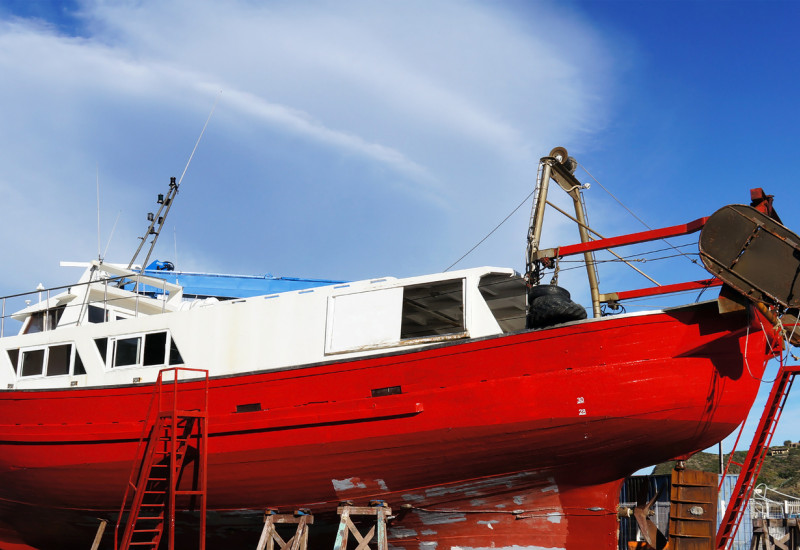 rotes Fischerboot liegt in der Werft, wird neu angestrichen