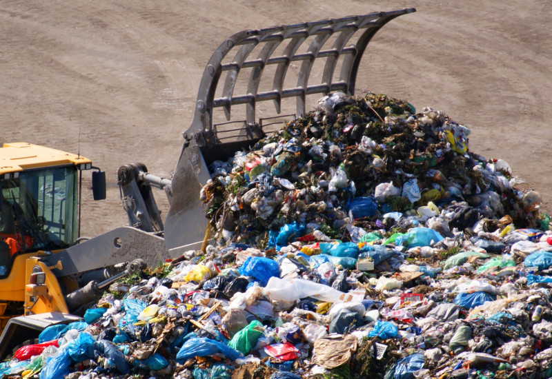 Ein Bagger schiebt den Müll der Abfalldeponie zusammen