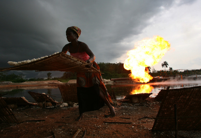 Afrikanische Frau arbeitet am Wasser, Feuer im Hintergrund