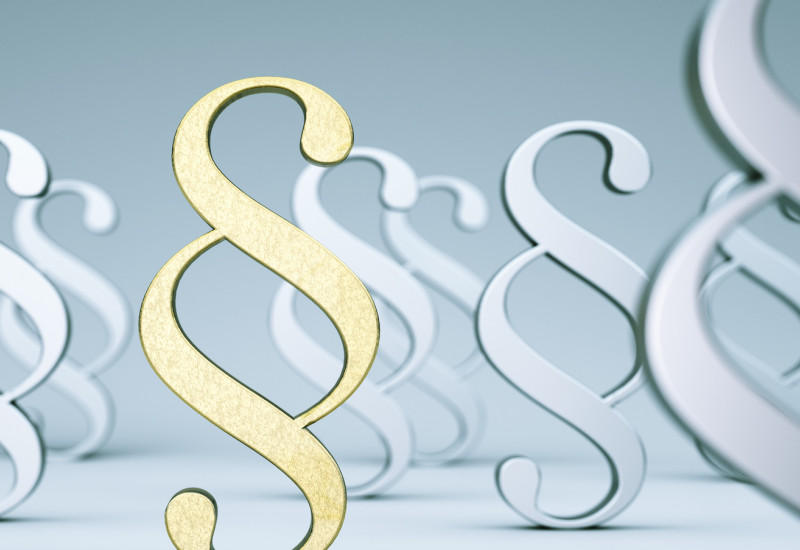goldenes Paragraphenzeichen umgeben von grauen und weißen Paragraphenzeichen