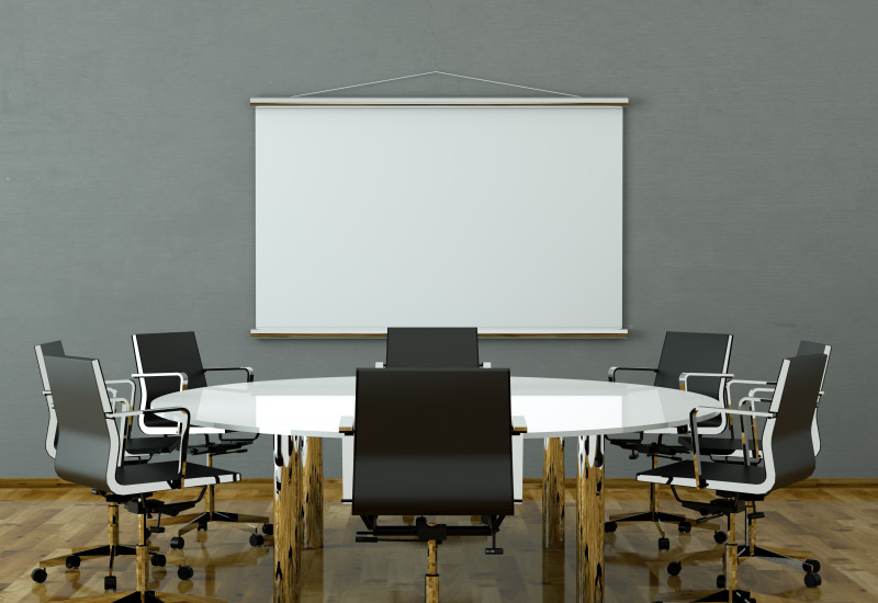 Konferenzzimmer mit hölzernem Bodenbelag, auf dem Tisch und Stühlen stehen