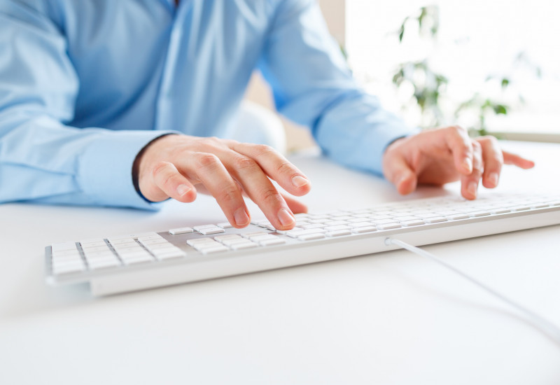 Mann tippt auf einer Computertatstatur