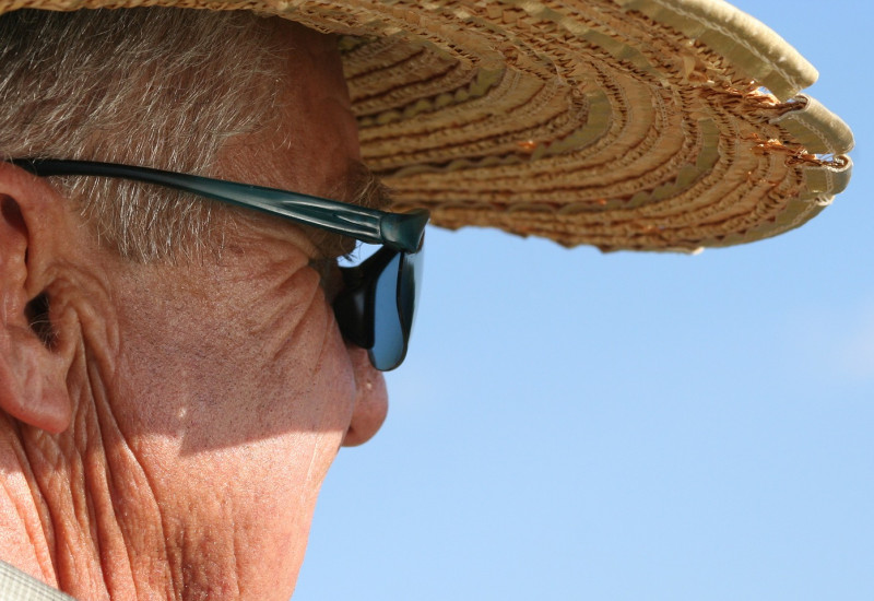 Älterer Mann mit Strohhut und Sonnenbrille