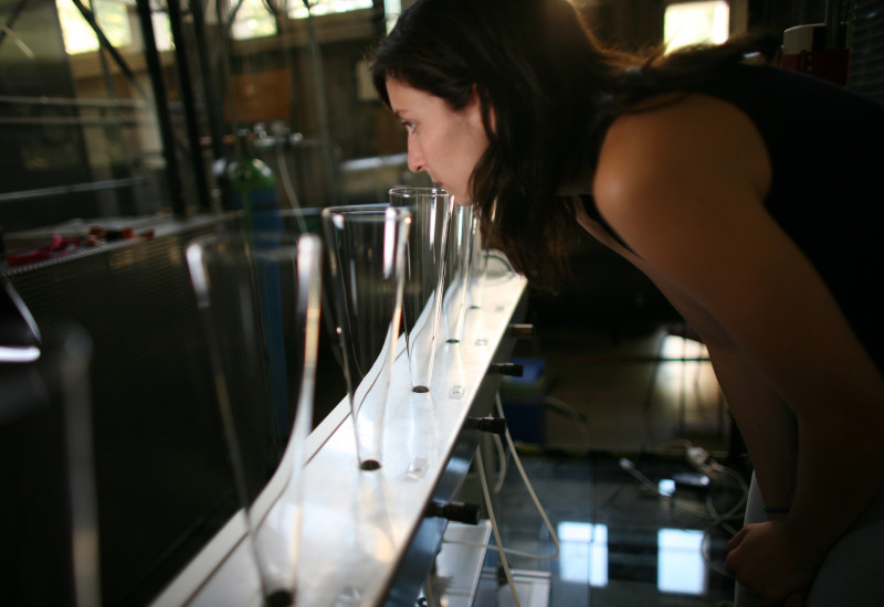 a young woman takes a smell at one of different glass plungers which are set out in a row