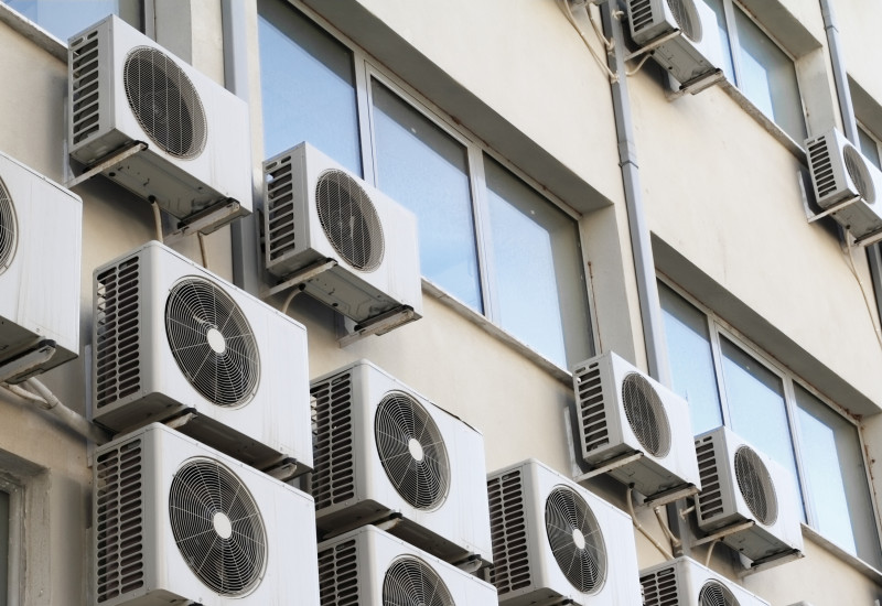 Viele kleine Klimaanlagen, die außen an einem Gebäude angebracht sind.