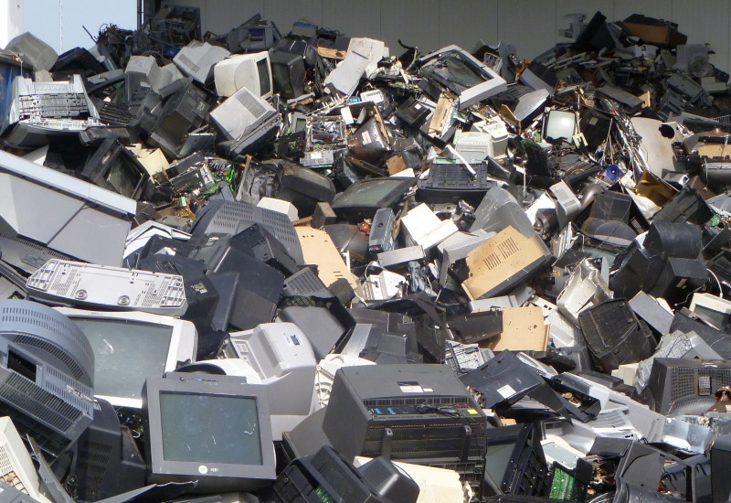 Old televisions and computer monitors on a pile.