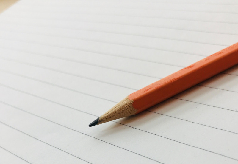 Ein Bleistift liegt auf einer linierten Seite Papier