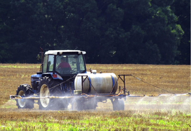 Ein Traktor sprüht Pflanzenschutzmittel auf ein Feld.