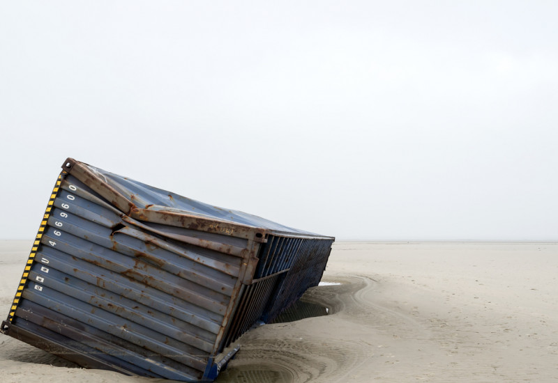 Ein havarierter Schiffscontainer liegt an einem Sandstrand.