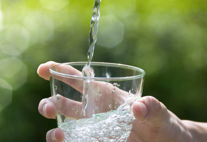 Eine Hand hält ein Glas unter einen Wasserhahn