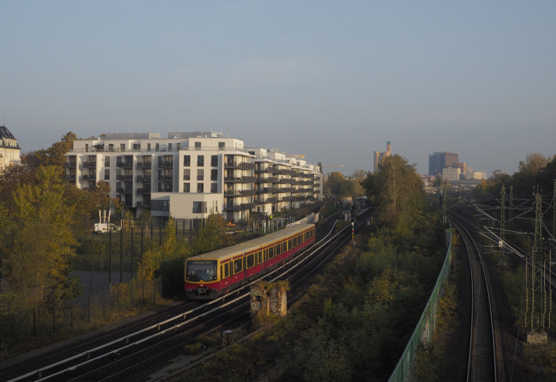 Blick auf Schienen mit einer S-Bahn, dahinter Stadtpanorama