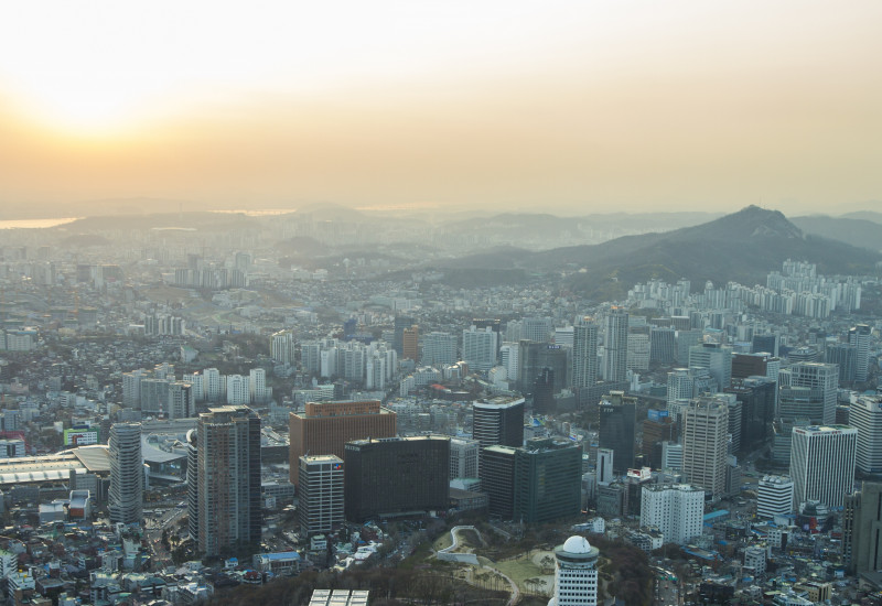 Blick über eine Großstadt, über der eine Smog-Wolke hängt; die Wolke verdecken fast die Sonne 