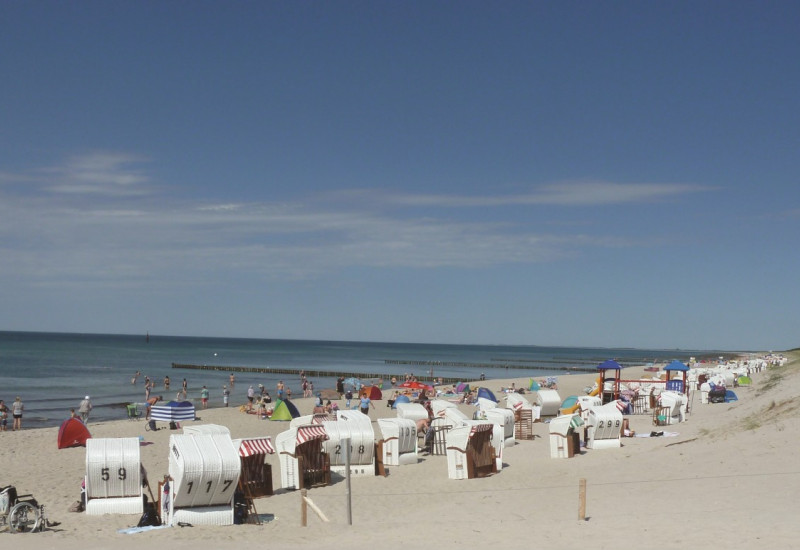 The picture shows a Baltic Sea beach with numerous beach chairs and the sea in bright weather.